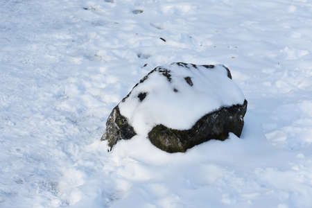Decorative stone covered with snow in the park.の写真素材