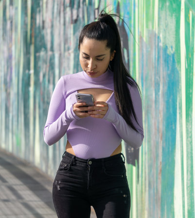 young girl sending a message with the mobile phone on the bridgeの写真素材