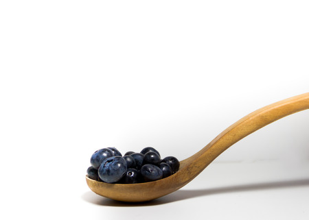 red fruits on white background and wooden spoonの写真素材