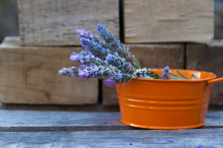 lavender flowers in an orange tin on rustic wooden backgroundの写真素材