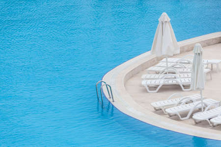 Curved side of a swimming pool with parasols and sunbedsの写真素材