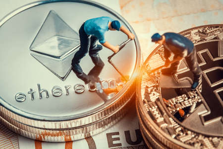 macro miner figurines working on stack of bitcoin and ethereum placed on euro banknote. virtual...