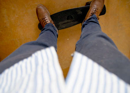 Man skating with brown boots and a beautiful blue shirt in brown floorの写真素材