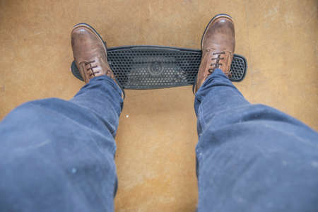 Man skating with brown boots and a beautiful blue shirt in brown floorの写真素材