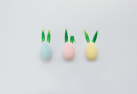 Colorful easter eggs with creative green bunny ears from leaves on a light blue backgroundの写真素材