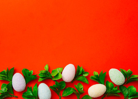 Red background pattern with copy space with coloful easter eggs and green leaves.の写真素材