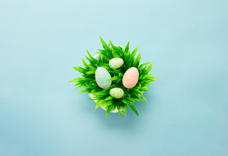 Easter eggs in a white plate with green leaves on a colorful light blue tiel background.の写真素材
