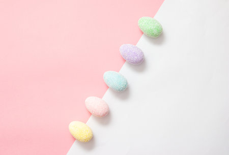 Colorful creative easter eggs on a pink and white background diagonally placed. Minimal creative art.の写真素材