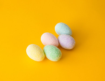 Colorful stacked up easter eggs on a bright yellow gold background. Creative minimal spring art.の写真素材