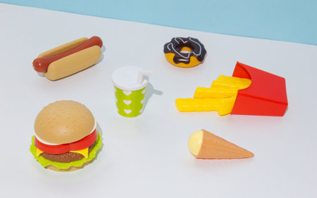 Fast food on a table with a blue bacgkround. Hamburger, hot dog, french fries, doughnut, ice cream, drink.の写真素材
