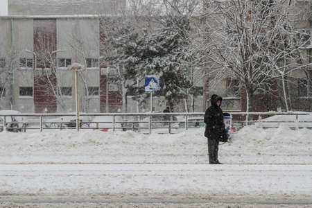 Bucharest, Romania, 17 January 2016: A woman is waiting for their route at the tram station during snowfall in Bucharest.のeditorial素材