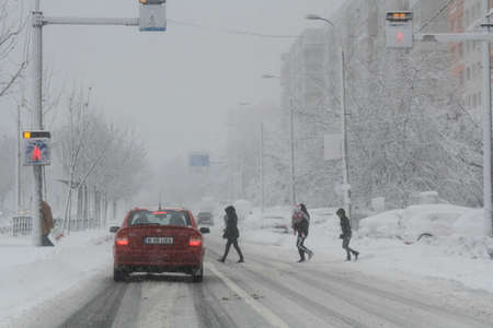 Bucharest, Romania, 17 January 2016: Pedestrians are crossing the street during a snowfall in Bucharest.のeditorial素材