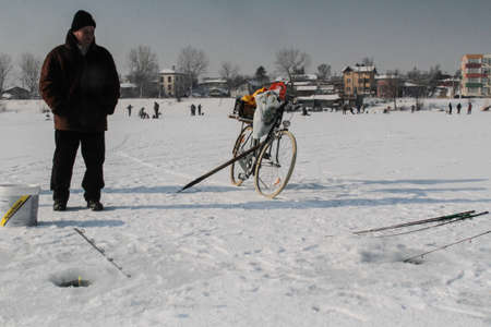 Bucharest, Romania, January 23, 2016: A man is fishing on a frozen lake in Bucharest on a cold day.