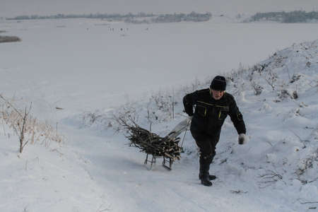 Bucharest, Romania, January 23, 2016: A man pull a sled filled with wood near to a frozen lake in Bucharest.のeditorial素材