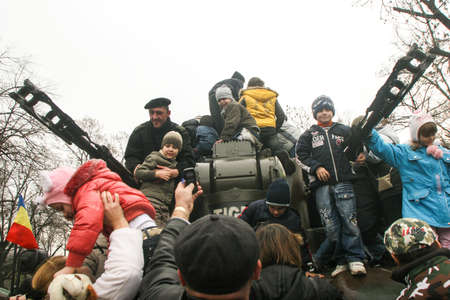 BUCHAREST, ROMANIA - DECEMBER 1, 2009: Children are playing on a tank during a military parade on National Day of Romania. More than 3,000 soldiers and personnel from security agencies take part in the massive parades on National Day of Romania.のeditorial素材