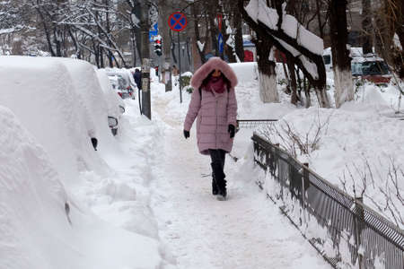 Bucharest, Romania, January 12, 2017: A woman walks on the street covered with snow in Bucharest.のeditorial素材