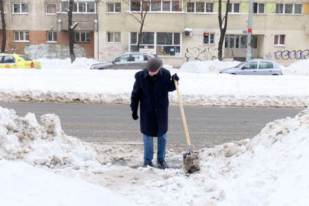 Bucharest, Romania, January 12, 2017: A man rests after shoveling a parking lot.のeditorial素材