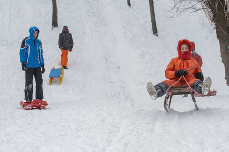 Bucharest, Romania, January 30, 2014: Children sleighing on a hill in a park in Bucharest, capital of Romania, during a cold day. The meteorologist announced temperatures lower than normal for this period.のeditorial素材