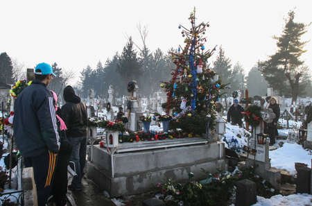 Bucharest, Romania, December 25, 2009: Gypsy people are praying at a grave of their relatives decorated with a Christmas tree, in a cemetery in Bucharest.のeditorial素材