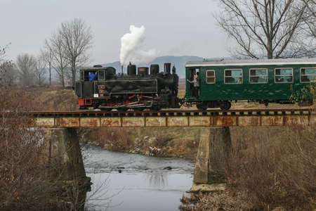 Brad, Romania, December12, 2009: An old steamed cog train is crossing a bridge in Brad, on winter holydays.のeditorial素材