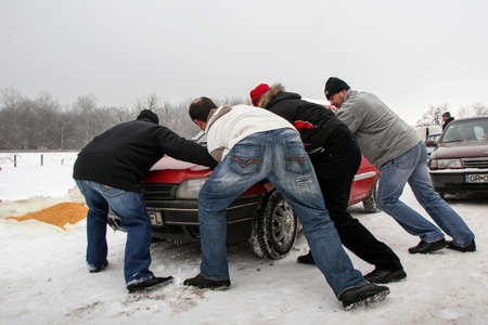 Calugareni, Romania, December 20, 2009: Four men are pushing a car in an animal market in...