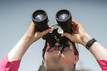 BUZAU, ROMANIA, June 18, 2016: A woman watches through the binocular during the BOBAS air show, on the Boboc aerodrome in Buzau.のeditorial素材