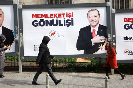 ISTANBUL, TURKEY - March 10, 2018: People walk past by AK Party billboards with pictures of Turkish President Tayyip Erdogan and mayoral candidate Binali Yildirim in Istanbul, Turkey.のeditorial素材