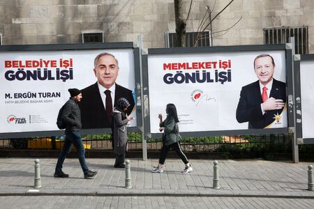 ISTANBUL, TURKEY - March 10, 2018: People walk past by AK Party billboards with pictures of Turkish President Tayyip Erdogan and mayoral candidate Binali Yildirim in Istanbul, Turkey.のeditorial素材