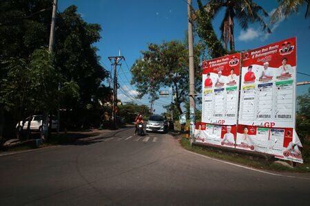 BALI, INDONESIA - April 07, 2019: A motorcyclist rides past a large election poster for Indonesian Presidential elections in Bali, Indonesia.のeditorial素材