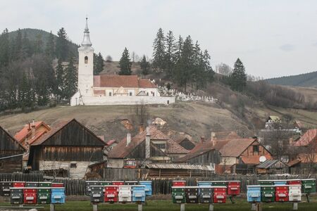 HARGHITA, ROMANIA - March 27, 2010: Country church in Lazarea, Harghita. Wooden beehive in front of the church.のeditorial素材