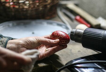 HARGHITA, ROMANIA - March 27, 2010: Woman drying paint on Easter eggs for exhibition.のeditorial素材