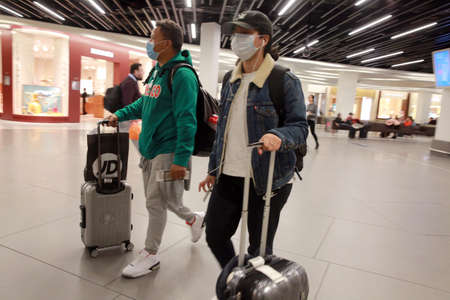 AMSTERDAM, NETHERLANDS - MARCH 13, 2020: People wear protective face mask as a preventive measure against the spread of the coronavirus in Amsterdam Airport Schiphol.のeditorial素材