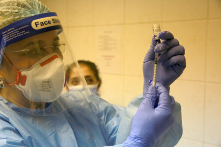 BUCHAREST, ROMANIA - Dec. 27, 2020: A nurse prepares a dose of the Pfizer-BioNTech COVID-19 vaccine during the first day of European Vaccination Campaign.のeditorial素材