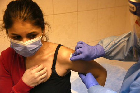 BUCHAREST, ROMANIA - Dec. 27, 2020: A member of medical personnel receives the covid vaccine during the first day of European Vaccination Campaign.のeditorial素材