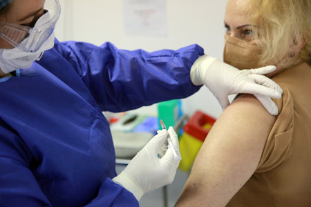 BUCHAREST, ROMANIA - Dec. 27, 2020: A member of medical personnel receives the covid vaccine during the first day of European Vaccination Campaign.のeditorial素材