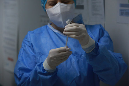 BUCHAREST, ROMANIA - Dec. 27, 2020: A nurse prepares a dose of the Pfizer-BioNTech COVID-19 vaccine during the first day of European Vaccination Campaign.のeditorial素材