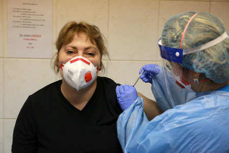 BUCHAREST, ROMANIA - Dec. 27, 2020: A member of medical personnel receives the covid vaccine during the first day of European Vaccination Campaign.のeditorial素材