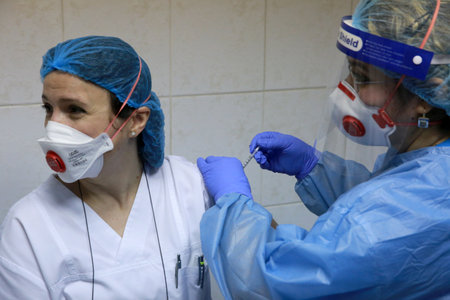 BUCHAREST, ROMANIA - Dec. 27, 2020: A member of medical personnel receives the covid vaccine during the first day of European Vaccination Campaign.のeditorial素材