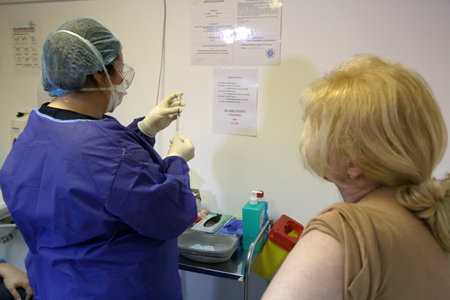 BUCHAREST, ROMANIA - Dec. 27, 2020: A member of medical personnel receives the covid vaccine during the first day of European Vaccination Campaign.のeditorial素材