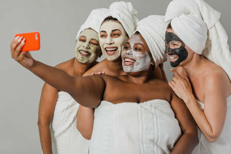 Multiethnic girlfriends taking selfie during spa sessionの写真素材