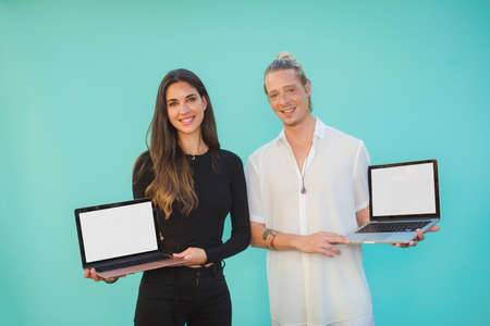 Smiling friends showing laptops with empty screensの写真素材