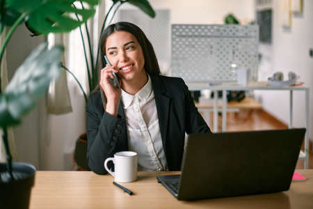 Young business woman using mobile phone inside modern office - Focus on faceの写真素材