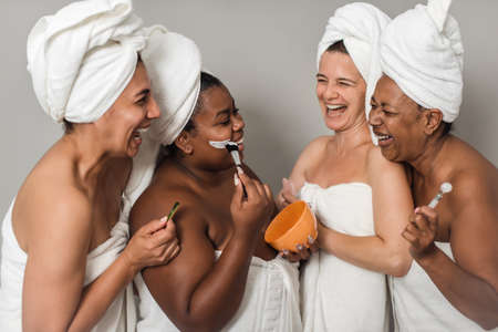 Multiracial girlfriends laughing during skin care procedureの写真素材