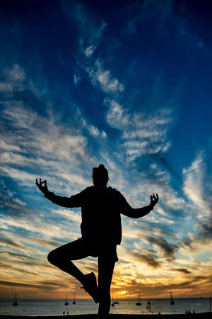 Happy woman doing meditation with beach on background during summer vacation - Focus on female silhouetteの写真素材