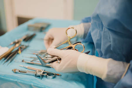Nurse doctor preparing surgical equipment for operation inside emergency hospital room - Focus on hand holding scissorsの写真素材