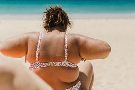 Plus size woman in bikini resting on beachの写真素材