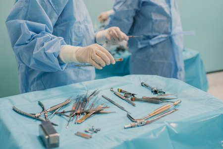 Medical team preparing surgical equipment for operation inside emergency hospital clinic - Focus on left doctor handの写真素材