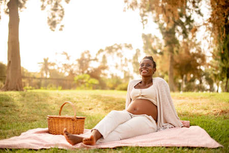 Delighted pregnant black woman relaxing in parkの写真素材
