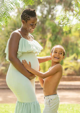 Happy black son touching belly of pregnant motherの写真素材