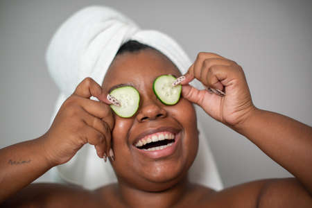 Black woman with cucumber slices on eyesの写真素材